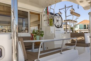 A boat's deck with a seating area, a steering wheel, and a potted plant.