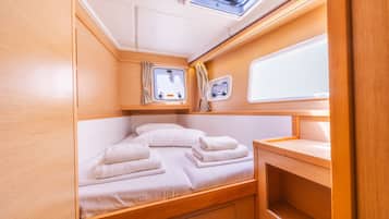 Ein gemütliches, helles Blockhäuschen mit einem Bett, einem kleinen Fenster und einem fest installierten Spülbecken.
