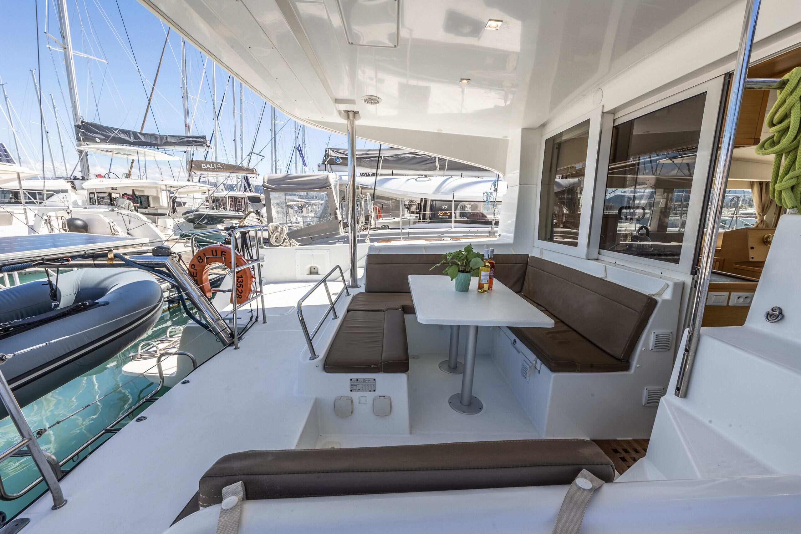 Ein Bootsdeck mit Sitzgelegenheit, einem Tisch und Blick auf andere Boote.