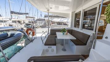 Ein Bootsdeck mit Sitzgelegenheit, einem Tisch und Blick auf andere Boote.