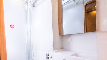 Une petite salle de bain comprenant des toilettes, une douche et un lavabo.