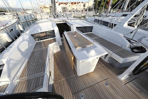A marina with boats docked, a wooden deck, and a white boat with a table and seating area.
