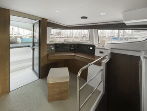 A boat's interior with a control panel, seating, and a view of the marina. - Sun-Kissed Sailing Adventure in Islas Sarónicas (Alimos)