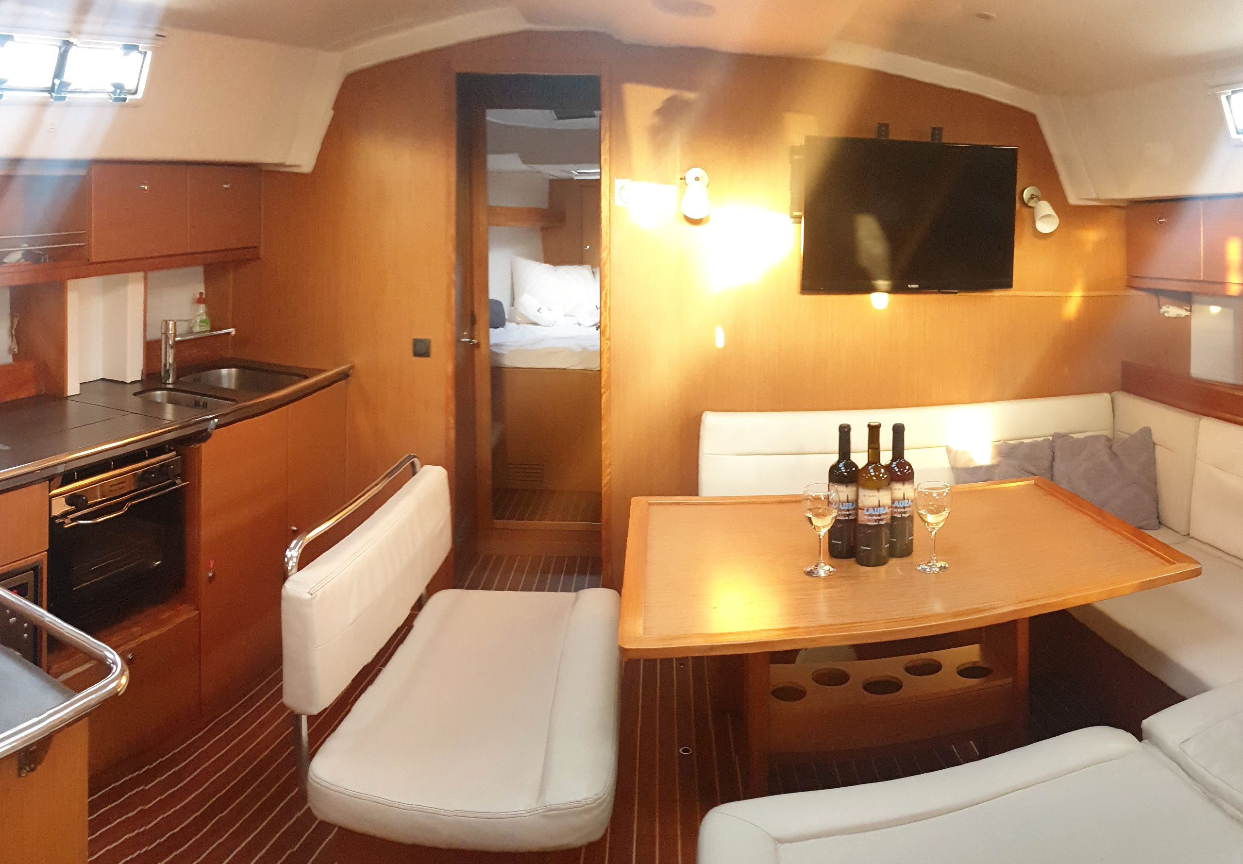 A compact kitchen with a sink, stove, and cabinets. There is a small dining area with a table and two chairs.