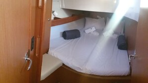 A compact cabin with a bunk bed, a small seating area, and a door leading to a bathroom.