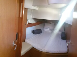 A compact cabin with a bunk bed, a small seating area, and a door leading to a bathroom.