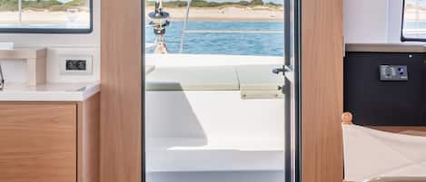 Un intérieur moderne avec une porte en bois donnant sur un espace extérieur, une petite cuisine et un coin salon avec vue sur la mer.