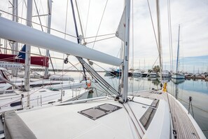 A marina with multiple sailboats docked, a clear sky, and calm water.