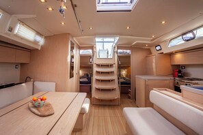 A compact, well-lit interior with a kitchenette, dining area, and a small bed. - Sun-Kissed Sailing Adventure in Islas Cícladas, Mykonos (Mykonos)