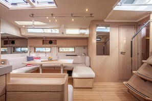 A compact RV interior with a dining area, seating, and a small kitchenette.