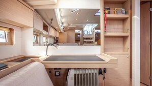 A compact, well-lit interior with a built-in sink, a cushioned seating area, and a mirrored wall reflecting the space. - Sun-Kissed Sailing Adventure in Islas Cícladas, Mykonos (Mykonos)