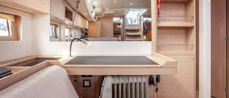 A compact, well-lit interior with a built-in sink, a cushioned seating area, and a mirrored wall reflecting the space.