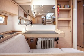 A compact, well-lit interior with a built-in sink, a cushioned seating area, and a mirrored wall reflecting the space. - Sun-Kissed Sailing Adventure in Islas Cícladas, Mykonos (Mykonos)