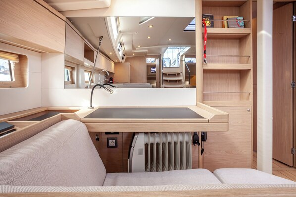 A compact, well-lit interior with a built-in sink, a cushioned seating area, and a mirrored wall reflecting the space.