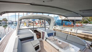 A boat's deck with seating, a small table, and a view of the marina. - Sun-Kissed Sailing Adventure in Islas Cícladas, Mykonos (Mykonos)