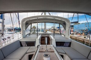 A boat's deck with seating, a central table, and a view of the marina.