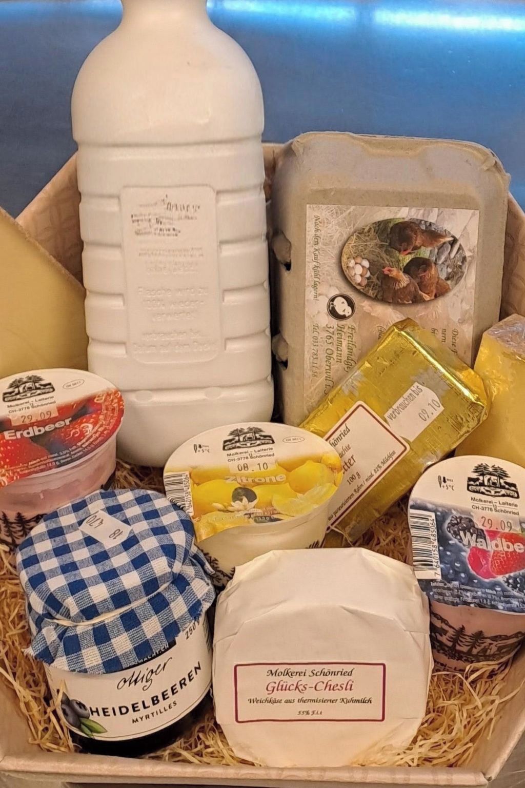 A variety of dairy products including cheese, yogurt, and milk in a wooden crate.