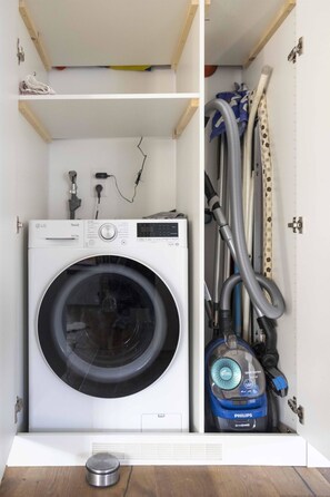 A compact laundry room with a front-loading LG ThinQ washer and a Philips vacuum cleaner. - Baren Penthouse Appartement/Fewo, Dusche, WC 8-Bettwohnung by Interhome (Zweisimmen)