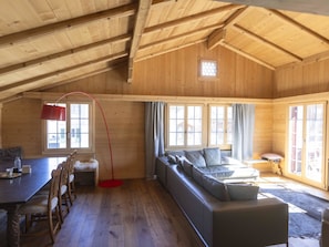 A spacious loft with a high ceiling, wooden beams, a dining area with a table and chairs, a sofa, and large windows allowing natural light. - Baren Penthouse Appartement/Fewo, Dusche, WC 8-Bettwohnung by Interhome (Zweisimmen)