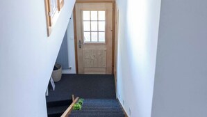 Una scala con tappeto scuro che conduce a una porta di legno in cima.