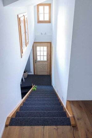 A staircase with dark carpeting leading to a wooden door at the top. - Baren Penthouse Appartement/Fewo, Dusche, WC 8-Bettwohnung by Interhome (Zweisimmen)