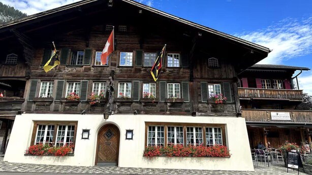 Un edificio in legno dal design tradizionale, con diverse finestre, un ingresso centrale e delle bandiere.