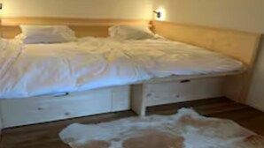 Una camera da letto con testiera in legno, un letto con biancheria bianca e un piccolo tappeto sul pavimento.
