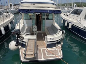 Ein Boot mit überdachter Sitzecke, einem kleinen Tisch und einem Wakeboard.