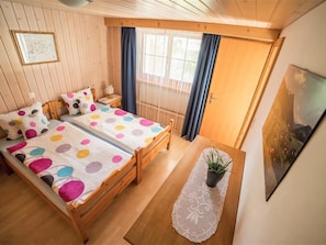 Ein gemütliches Schlafzimmer mit einem hölzernen Bett, einem kleinen Nachttisch und einem Fenster mit Vorhängen.