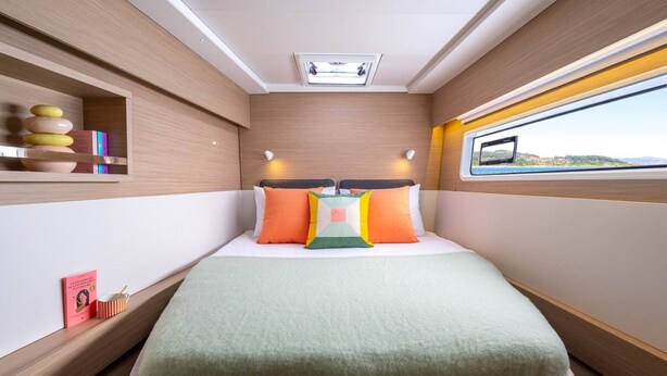 Ein gemütliches, gut beleuchtetes Blockhaus mit einem Bett, einem Regal mit Büchern, einem kleinen Tisch mit einer Tasse und einem Fenster mit Blick.
