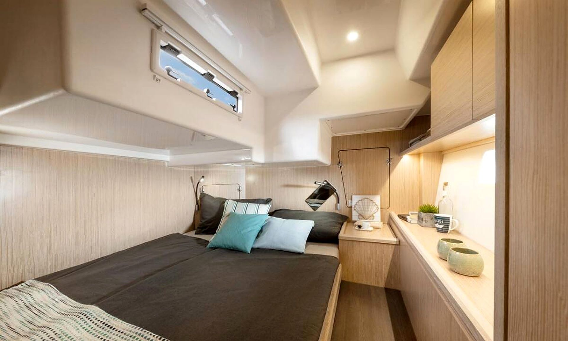 Ein gemütliches Schlafzimmer mit Bett, Nachttisch, Lampe und kleinem Fenster.