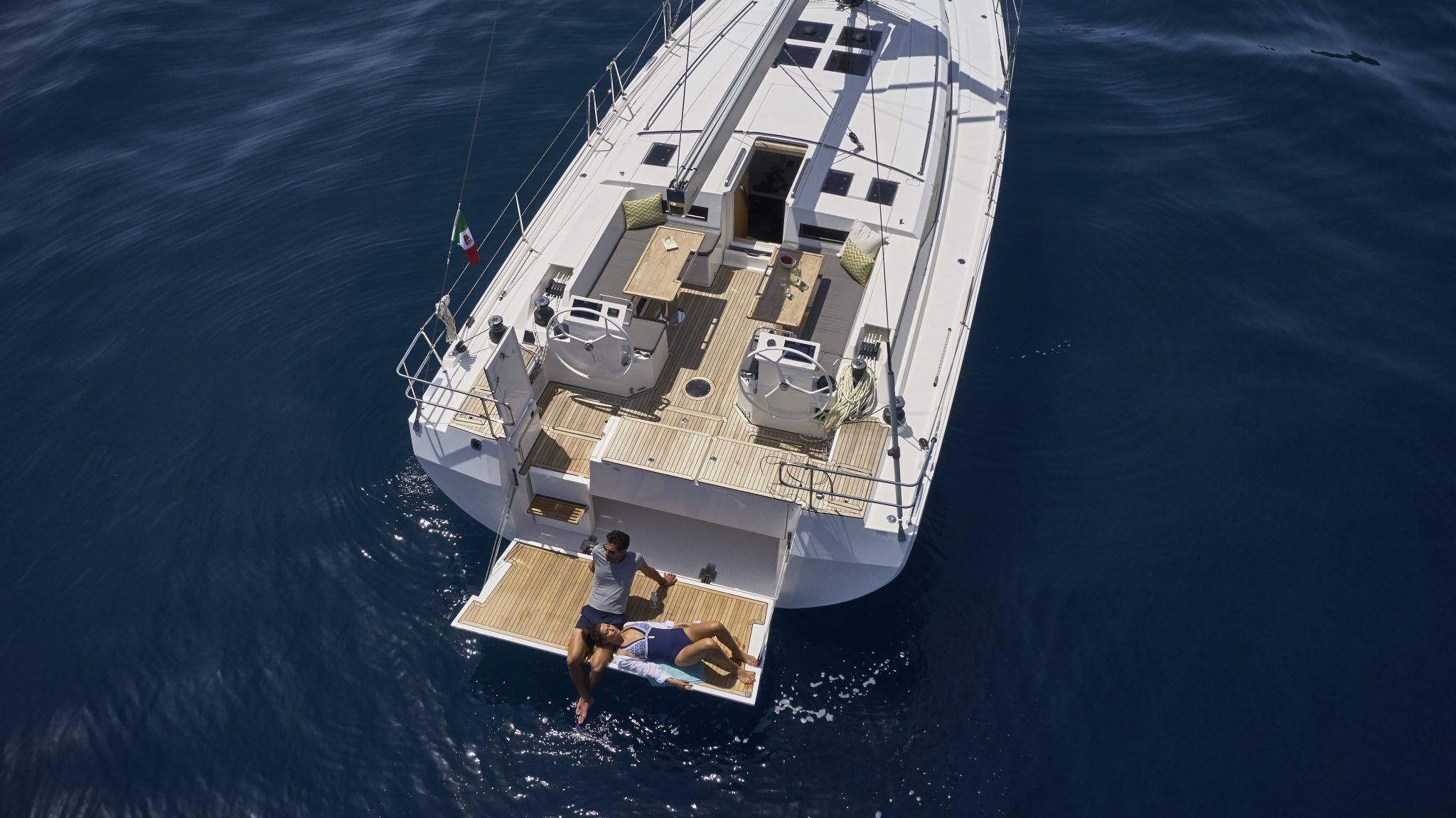 Een zeilboot met een dekgedeelte met zitplaatsen en een kleine tafel, omringd door water.