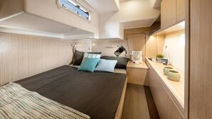 Ein kompakter, gut beleuchteter Innenraum mit einem Bett, einem Nachttisch und einem kleinen Fenster.