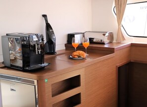 Una kitchenette con cafetera, tostadora y dos vasos de jugo de naranja sobre la encimera.
