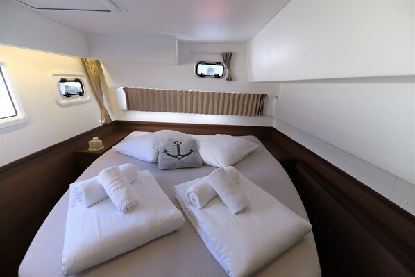 A room with a bed, pillows, a window, a small table, and a curtain. - Sun-Kissed Sailing Adventure in Zadar, Croatia (Zadar)