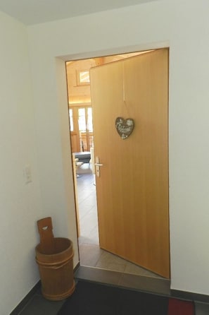 A wooden door with a heart-shaped welcome sign, a wooden bucket, and a tiled floor. - Majelas Heiti Appartement/Fewo, Dusche und Bad, WC 6-Bettwohnung by Interhome (Gsteig bei Gstaad)