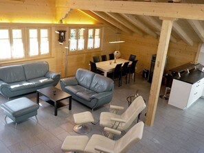Ein geräumiger Wohnbereich mit einer Couch, einem Esstisch und einer Küchenzeile.