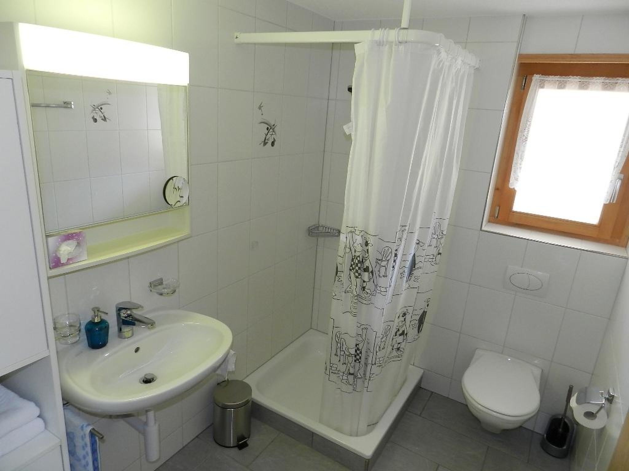 Ein Badezimmer mit Dusche, Toilette, Waschbecken und einem Fenster.