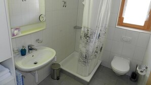 Ein Badezimmer mit Dusche, Toilette, Waschbecken und einem Fenster.