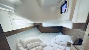 Een compact vakantiehuisje met goede verlichting, een enkel bed, netjes opgevouwen handdoeken en een klein raam.