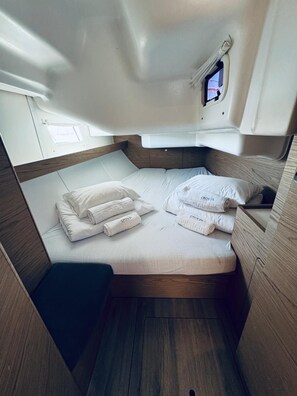 A compact, well-lit cabin with a single bed, neatly folded towels, and a small window. - Sun-Kissed Sailing Adventure in Northern Croatia (Novi Vinodolski)