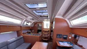 A compact interior with a dining table, two sofas, a kitchen area, and overhead windows. - Sun-Kissed Sailing Adventure in Zadar, Croatia (Bibinje)