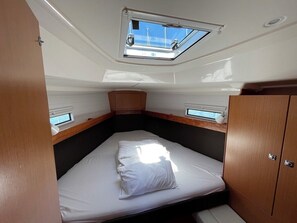 A compact cabin with a skylight, a bed, and a small seating area. - Sun-Kissed Sailing Adventure in Zadar, Croatia (Bibinje)