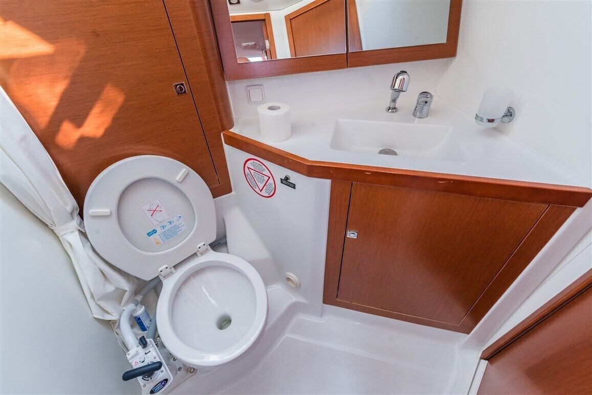 A bathroom with a toilet, sink, and mirror.