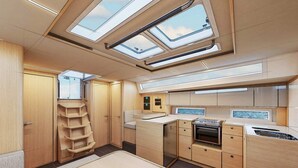 Une cuisine compacte dotée d’appareils électroménagers intégrés, un petit coin repas et des fenêtres de toit.