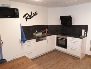 A modern kitchen with white cabinets, a black countertop, and a microwave.
