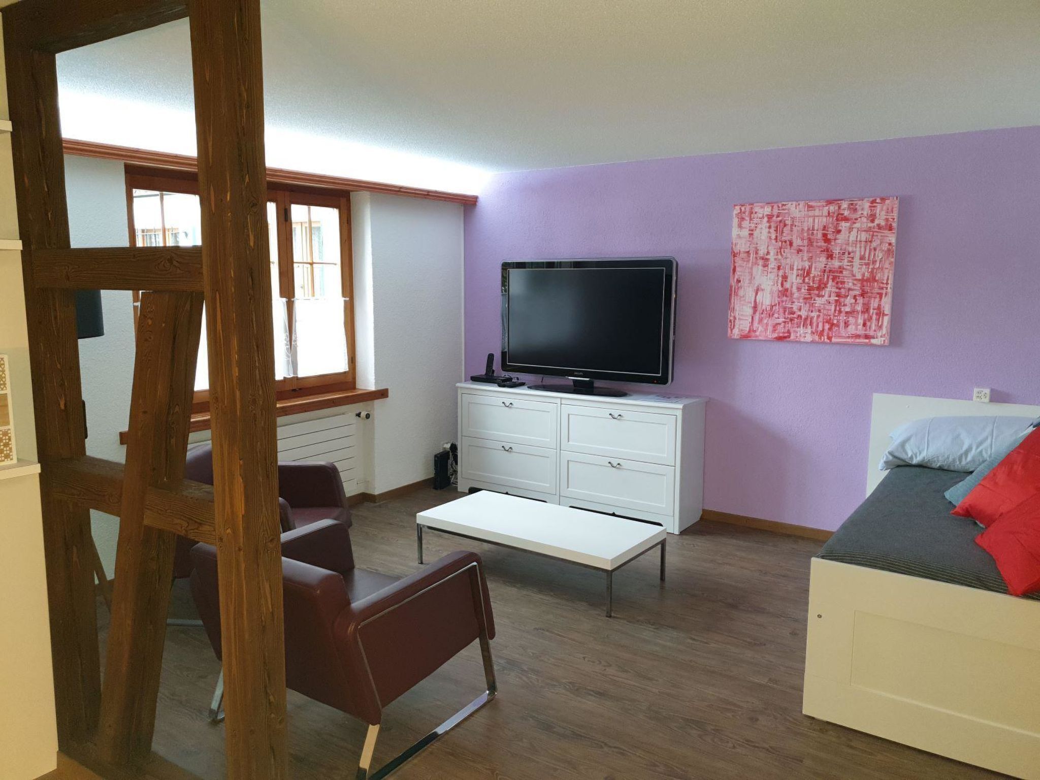 A room with a bed, a TV, a desk, and a chair.