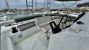 Le pont d’un bateau, avec un volant, un panneau de commande et un espace pour s’asseoir.