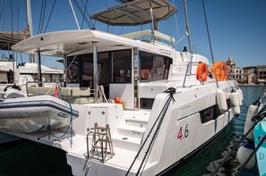 Eine weiße Yacht liegt in einer Marina festgemacht, mit überdachter Deck, Rettungsringen und einer Kabine mit Fenstern.