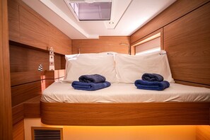 Une chambre à coucher de taille modeste, dotée d’une lucarne, de murs en bois, d’un lit avec du linge de lit blanc et de deux serviettes pliées.